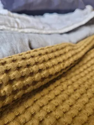 a close up of a yellow blanket on a bed at Tylda Tents at Tregonetha Lake - 5m Luxury Bell Tent 