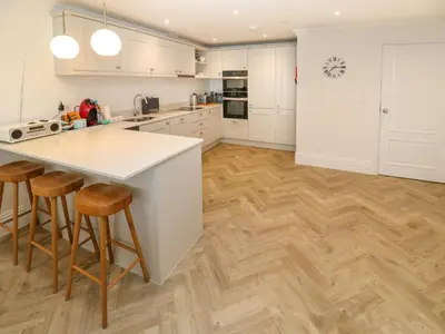 a kitchen with white cabinets and wooden floors at Amelia's Point in St Ives