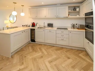 a kitchen with white cabinets and a wooden floor at Amelia's Point in St Ives
