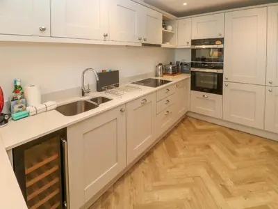 a kitchen with white cabinets and a wooden floor at Amelia's Point in St Ives