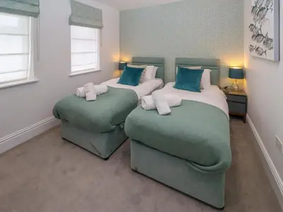 two beds in a room with two ottomans at Amelia's Point in St Ives