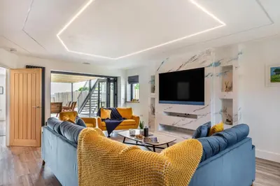 a living room with a blue couch and yellow chairs at 4 Bed in Windmill oc-w29654 in St Merryn