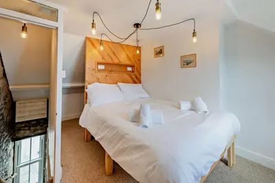 a bedroom with a large white bed and a fireplace at 2 Bed in Looe oc-a29612 in Looe