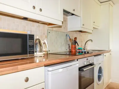 a kitchen with white cabinets and a microwave at Bray Cottage in Bodmin