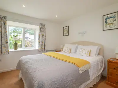 a bedroom with a large bed and a window at Bray Cottage in Bodmin