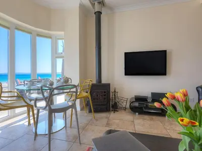 a living room with a dining table and a television at Seaspray in St Ives