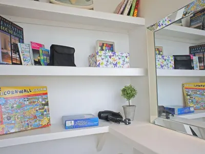a shelf with books and a mirror in a room at Seaspray in St Ives