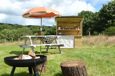 a picnic table with an umbrella and a grill at Tylda Tents at Heydaze Campsite - 5m Luxury Bell Tent 