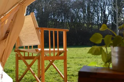 a wooden chair sitting in a field of grass at Tylda Tents at Heydaze Campsite - 5m Luxury Bell Tent 