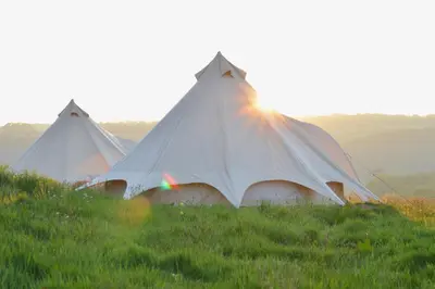 three tents in a field with the sun behind them at Tylda Tents at Heydaze Campsite - 5m Luxury Bell Tent 
