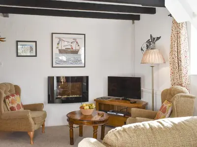 a living room with a couch and a tv at Penny's Cottage-Uk12572 in Bodinnick