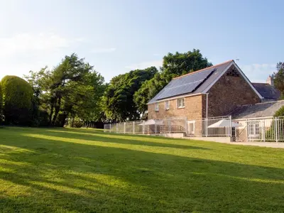 a large grassy yard in front of a brick building at Penny's Cottage-Uk12572 in Bodinnick