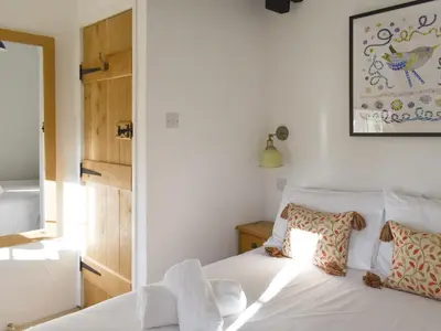 a bedroom with a white bed with two pillows at Penny's Cottage-Uk12572 in Bodinnick