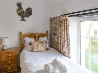a bed with a teddy bear sitting on top of it at Penny's Cottage-Uk12572 in Bodinnick
