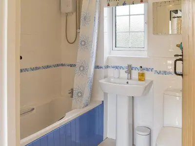 a bathroom with a sink and a tub and a toilet at Penny's Cottage-Uk12572 in Bodinnick