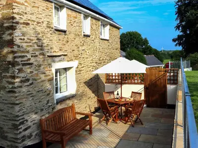 a patio with a table and chairs and a building at Penny's Cottage-Uk12572 in Bodinnick