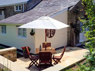 a table with a white umbrella on a patio at The Linney-Uk12576 in Bodinnick