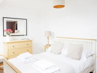 a bedroom with a white bed with towels on it at April Cottage in Padstow