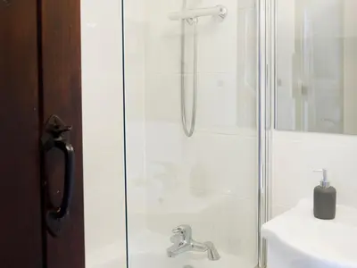 a shower with a glass door next to a sink at April Cottage in Padstow