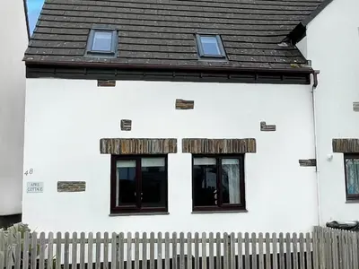 a white house with two windows and a fence at April Cottage in Padstow