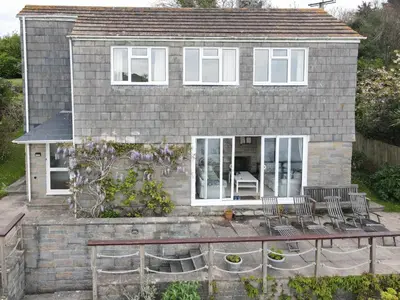 a house with chairs and a patio in front of it at Harbourside in Fowey