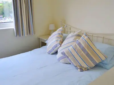 a bed with three pillows on it with a window at Harbourside in Fowey