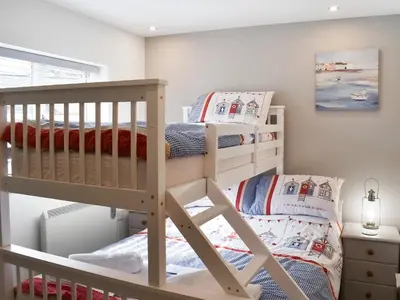 two bunk beds in a childs room with a ladder at 15 Pebble Cottage in Camelford