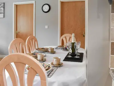 a table with plates and cups and a bottle of wine at 15 Pebble Cottage in Camelford