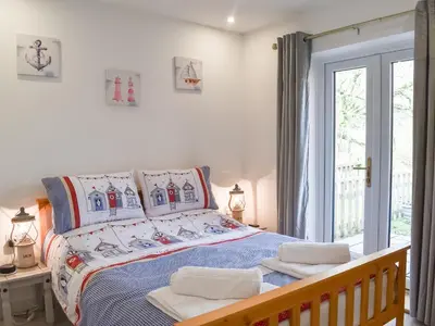 a bedroom with a bed and a window at 15 Pebble Cottage in Camelford