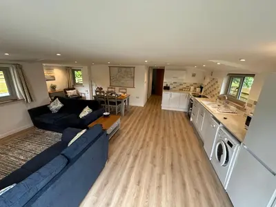 a living room with a blue couch and a kitchen at The Stables at Hustyn Gate in Wadebridge