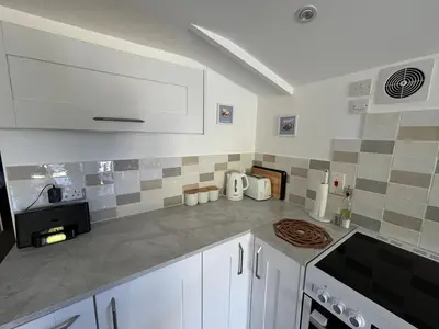 a kitchen with white cabinets and a counter top at The Stables at Hustyn Gate in Wadebridge