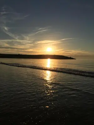 a sunset on the beach with the sun setting at The Stables at Hustyn Gate in Wadebridge