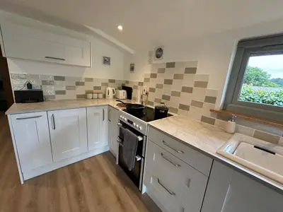 a kitchen with white cabinets and a sink at The Stables at Hustyn Gate in Wadebridge