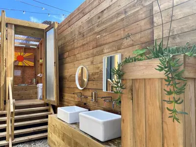 a bathroom with two sinks and a wooden wall at Lakeside Glamping Kingfisher in Saint Columb Major