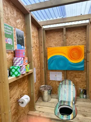 a bathroom with a toilet and a painting on the wall at Lakeside Glamping Kingfisher in Saint Columb Major