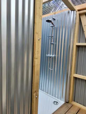 a shower with a shower head in a shed at Lakeside Glamping Firecrest in Saint Columb Major