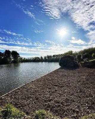 a body of water with the sun in the sky at Lakeside Glamping Firecrest in Saint Columb Major