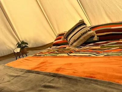 a bed with a pillow in a tent at Lakeside Glamping Firecrest in Saint Columb Major