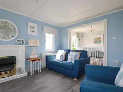 a blue living room with a blue couch and a fireplace at Lowen Lodge in Padstow