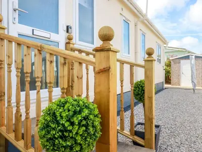 a wooden railing with a bush in front of a house at Lowen Lodge in Padstow