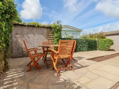 a table and two chairs sitting next to a wall at Lowen Lodge in Padstow