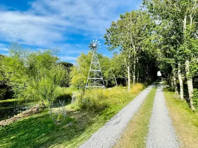 a dirt road with a windmill in the distance at The Garden Room - Cabin on The Lizard in Cury