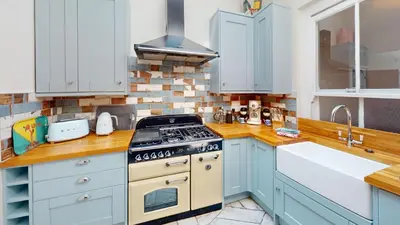 a kitchen with blue cabinets and a stove top oven at St Ives Bubblegum Cottage in St Ives