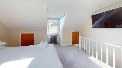 a bedroom with a white bed and a large window at St Ives Bubblegum Cottage in St Ives