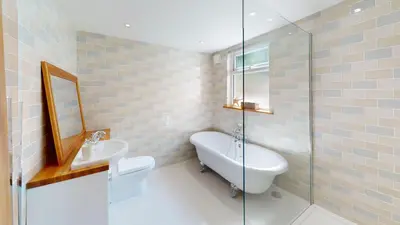 a bathroom with a sink and a toilet and a mirror at St Ives Bubblegum Cottage in St Ives