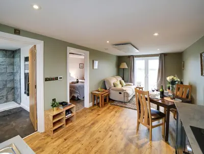 a living room with a table and a dining room at The Tractor Shed, a romantic barn retreat on the edge of Falmouth in Budock Water
