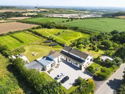 an aerial view of a house in a field at The Tractor Shed, a romantic barn retreat on the edge of Falmouth in Budock Water