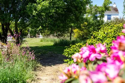 a garden with pink flowers in front of a house at The Tractor Shed, a romantic barn retreat on the edge of Falmouth in Budock Water