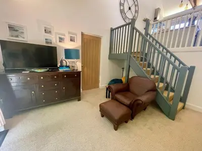 a living room with a staircase and a chair at Cornwall Truro Falmouth cottage in Perranwell