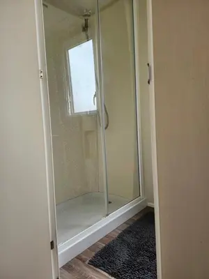 a glass shower in a room with a window at Chapmans Holiday Home Newquay in Newquay